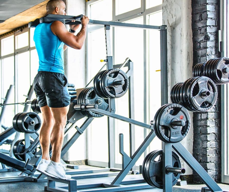 man doing standing calf raise machine in gym