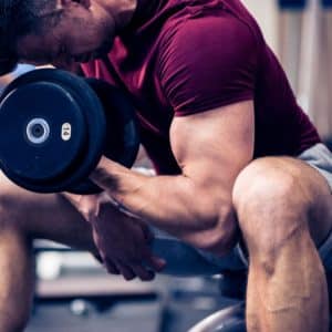 man strengthening biceps in gym with weights