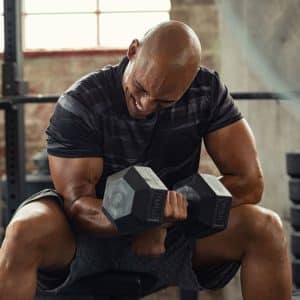 man gaining muscle lifting dumbbell weight on bench