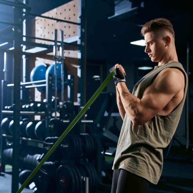 man resistance training with resistance bands in gym